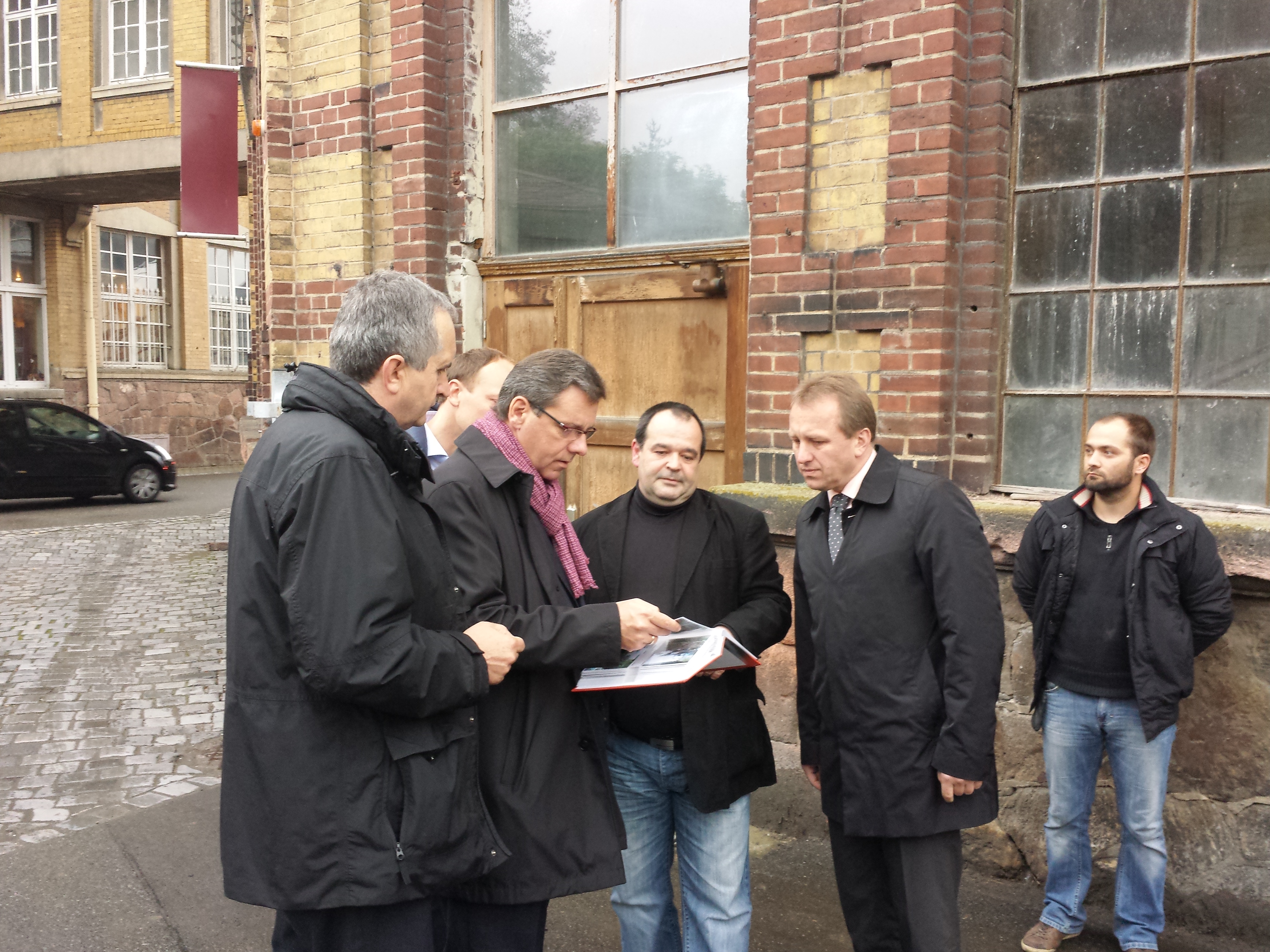 Geschäftsführer Holger Reichel zeigt Staatsminister Frank Kupfer MdL, Marco Wanderwitz MdB, Bürgermeister Ronny Hofmann und Thomas Schmidt MdL Bilder von der Zerstörung aufgrund des Juni-Hochwassers.